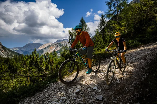 Cycling woman and man riding on bikes in Dolomites mountains and