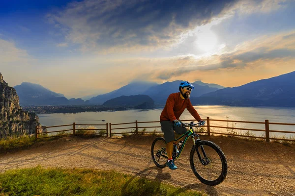 Ciclista uomo in bicicletta in bicicletta al sorgere del sole montagne e lago di Garda l — Foto Stock