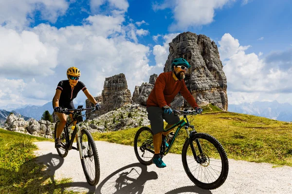 Cycling woman and man riding on bikes in Dolomites mountains lan