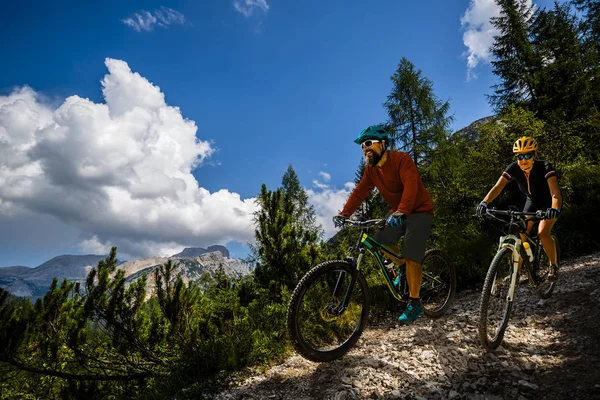 Cycling woman and man riding on bikes in Dolomites mountains and