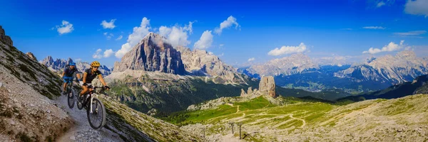 Cycling woman and man riding on bikes in Dolomites mountains lan