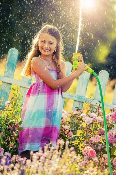 Playfull menina regando flores com chuva no jardim no verão — Fotografia de Stock