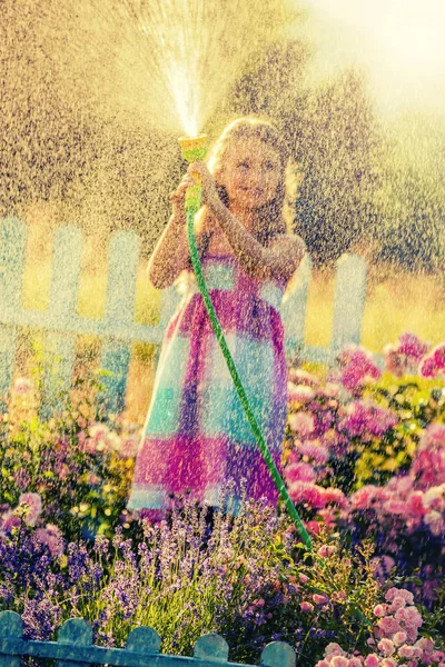 遊び心の女の子の夏の庭の雨と花の水やり — ストック写真