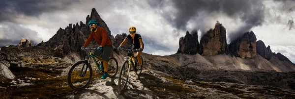 Cycling woman and man riding on bikes in Dolomites mountains and — Stock Photo, Image