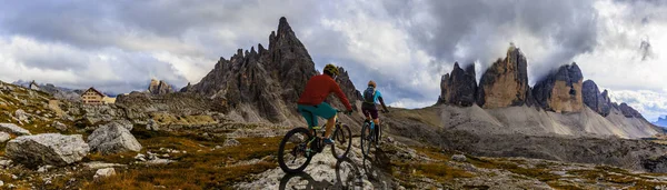 Ciclismo mulher e homem andando de bicicleta em Dolomites montanhas e — Fotografia de Stock