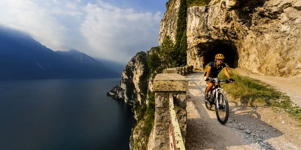 Mountain cykling kvinna vid soluppgången över Gardasjön på väg Sentier — Stockfoto