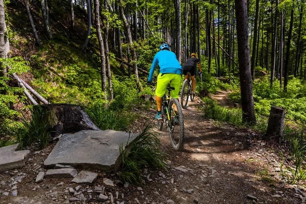 Fietsen van de vrouw en mannen rijden op de fiets bij zonsondergang bergen forest — Stockfoto