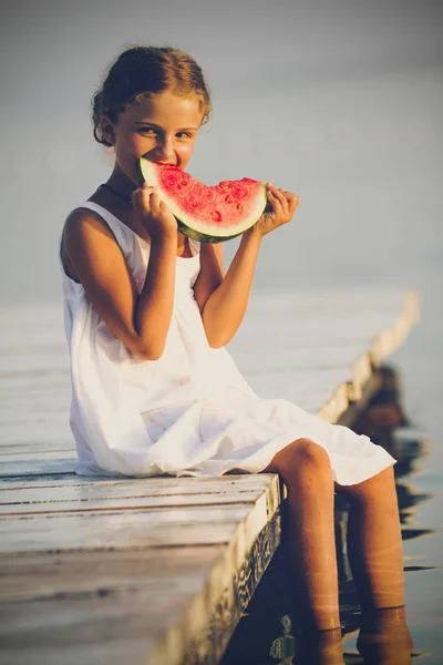 Mladá dívka držící meloun, který sedí na dřevěném mostě. Souhr — Stock fotografie