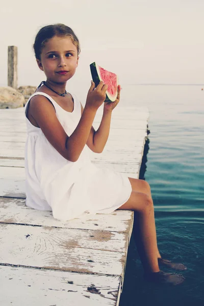 Junges Mädchen mit Wassermelone auf der Holzbrücke sitzend. summ — Stockfoto