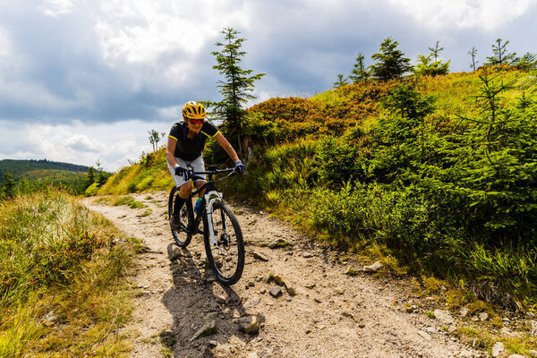 Mountain biking woman riding on bike in summer mountains forest 