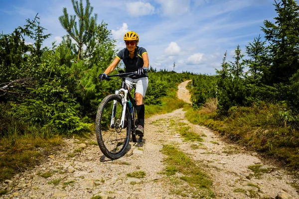 Cycling woman riding on bike in autumn mountains forest landscap