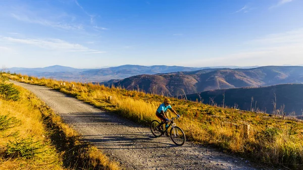 Cycling woman riding on bike in autumn mountains forest landscap