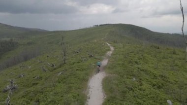 Yaz dağları manzarasında bisikletli bir kadının hava görüntüsü. MTB kullanan kadın.
