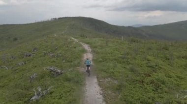 Yaz dağları manzarasında bisikletli bir kadının hava görüntüsü. MTB kullanan kadın.