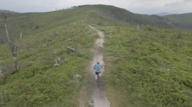 Yaz dağları manzarasında bisikletli bir kadının hava görüntüsü. MTB kullanan kadın.