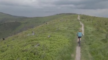 Yaz dağları manzarasında bisikletli bir kadının hava görüntüsü. MTB kullanan kadın.