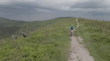 Yaz dağları manzarasında bisikletli bir kadının hava görüntüsü. MTB kullanan kadın.