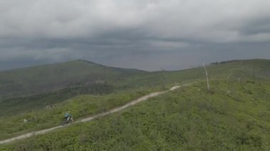 Yaz dağları manzarasında bisikletli bir kadının hava görüntüsü. MTB kullanan kadın.