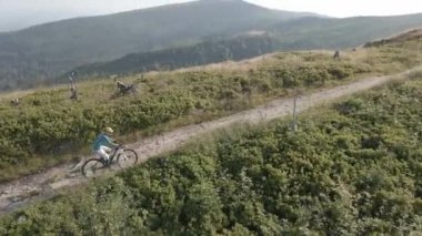 Yaz dağları manzarasında bisikletli bir kadının hava görüntüsü. MTB kullanan kadın.