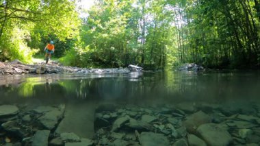 Bisikletli bir adam dağ nehrinden karşıya geçerken su sıçrıyor. Bisikletli bir adam dağ nehrinden geçerken su sıçrıyor..