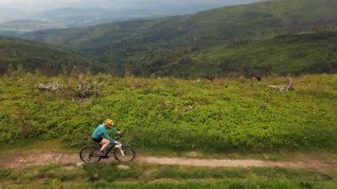 Yaz dağları manzarasında bisikletli bir kadının hava görüntüsü. MTB 'de bisiklet süren kadın. Açık hava macerası. Çakıl taşı yolu..