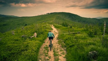 Yaz dağları manzarasında bisikletli bir kadının hava görüntüsü. MTB 'de bisiklet süren kadın. Açık hava macerası. Çakıl taşı yolu..
