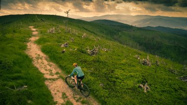Yaz dağları manzarasında bisikletli bir kadının hava görüntüsü. MTB 'de bisiklet süren kadın. Açık hava macerası. Çakıl taşı yolu..