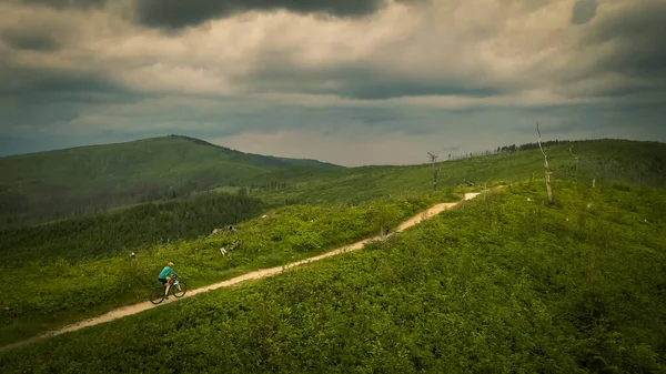 夏の山の風景の中に自転車に乗ってマウンテンバイクの女性の空中ショット 女性サイクリングMtbアウトドアアドベンチャー砂利シングルトレイル — ストック写真