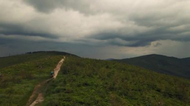 Yaz dağları manzarasında bisikletli bir kadının hava görüntüsü. MTB 'de bisiklet süren kadın. Açık hava macerası. Çakıl taşı yolu..