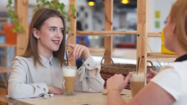 Kafede oturup kahve içen iki genç kadın..