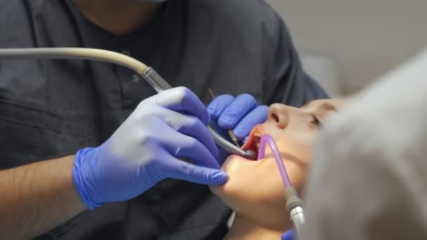 Odontólogo masculino tratando dientes a paciente joven en clínica . — Vídeos de Stock