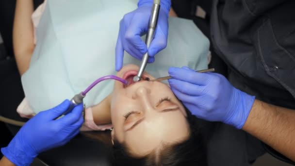 Male dentist treating teeth to young woman patient in clinic. — Stock Video