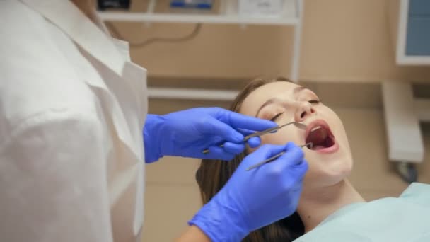 Vrouwelijk tandarts behandeling tanden aan jonge vrouw patiënt in kliniek. — Stockvideo