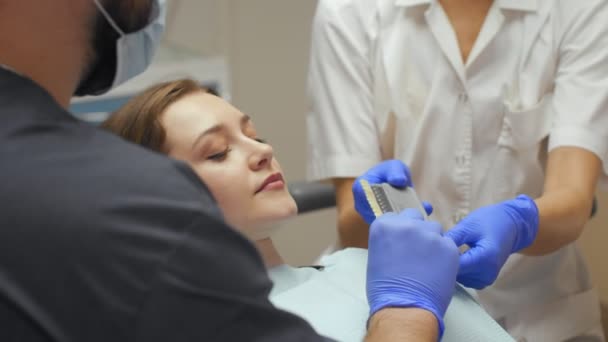 Odontólogo masculino tratando dientes a paciente joven en clínica . — Vídeos de Stock