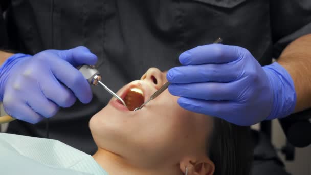 Muž zubař léčení zuby na mladou ženu pacienta na klinice.