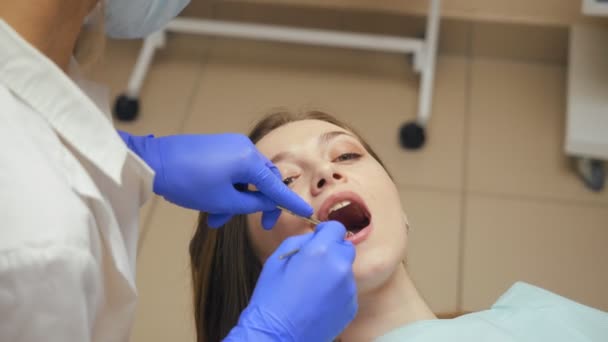 Dentista que trata los dientes a una paciente joven en la clínica . — Vídeo de stock