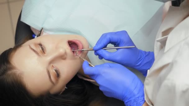 Female dentist treating teeth to young woman patient in clinic. — Stock Video