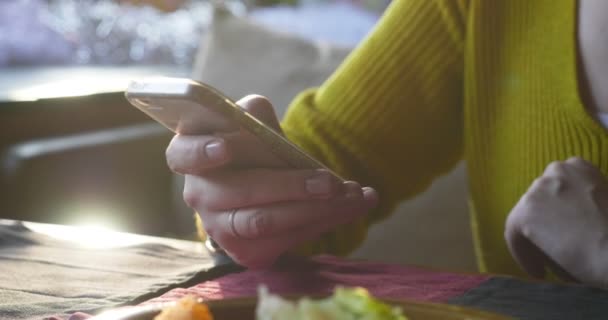 Vrouw in het café met behulp van de smartphone tijdens het wachten. — Stockvideo