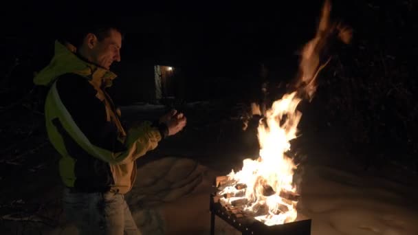 Homme près de brasero avec le feu et chauffe ses mains en hiver . — Video