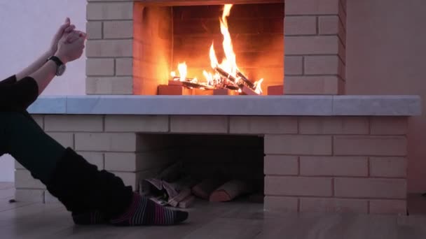 Vrouw opwarming van de aarde haar handen bij brand open haard. — Stockvideo
