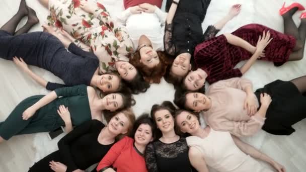 Top view on happy women in dress lying on the floor. — Stock Video