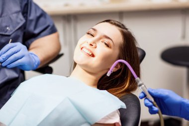 Klinikte dişlerini tedavi eden erkek dişçi..