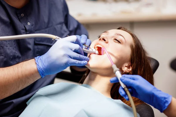 Odontólogo masculino tratando dientes a paciente joven en clínica . —  Fotos de Stock