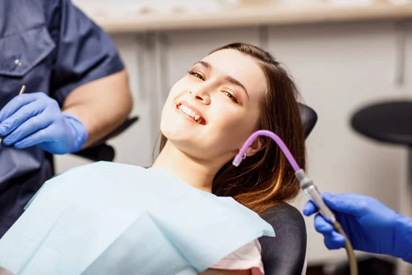 Odontoiatra di sesso maschile che cura i denti alla giovane paziente in clinica . — Foto Stock