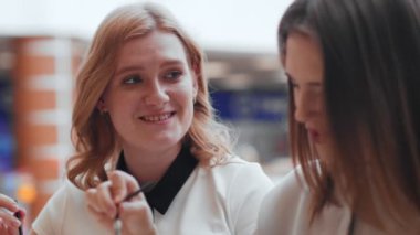 Kafede oturup kahve içen iki genç kadın..