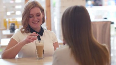 Kafede oturup kahve içen iki genç kadın..