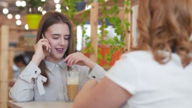 Kafede oturup kahve içen iki genç kadın..