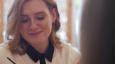 Kahve içme ve FRIEN Cafe ile konuşan genç kadın.