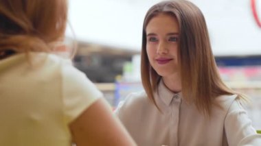 Kafede oturan ve konuşurken iki genç kadın.