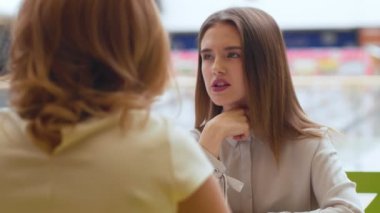 Kafede oturan ve konuşurken iki genç kadın.